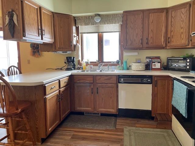 kitchen featuring a toaster, white dishwasher, range with electric cooktop, a sink, and brown cabinets