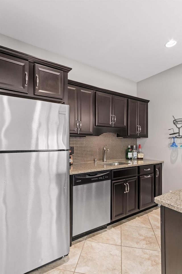 784 Westbridge Trl, Waunakee, WI 53597 - kitchen featuring light stone counters, a sink, stainless steel appliances, dark brown cabinetry, and backsplash