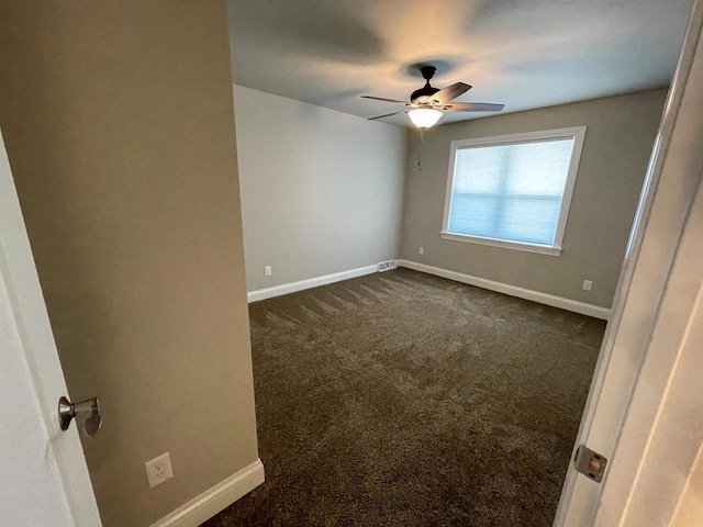 unfurnished bedroom with baseboards, a ceiling fan, and dark carpet