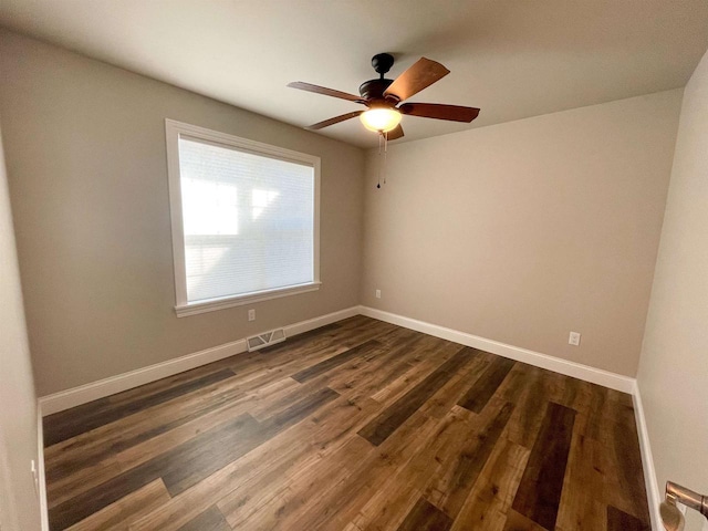 empty room featuring ceiling fan, dark wood-style floors, visible vents, and baseboards