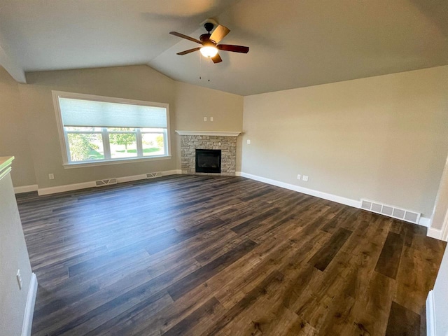 unfurnished living room featuring visible vents, dark wood-type flooring, a ceiling fan, a stone fireplace, and vaulted ceiling