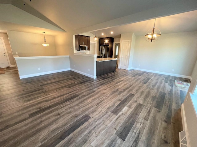 unfurnished living room with lofted ceiling, a notable chandelier, baseboards, and dark wood-type flooring