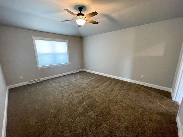 spare room featuring visible vents, dark carpet, baseboards, and vaulted ceiling