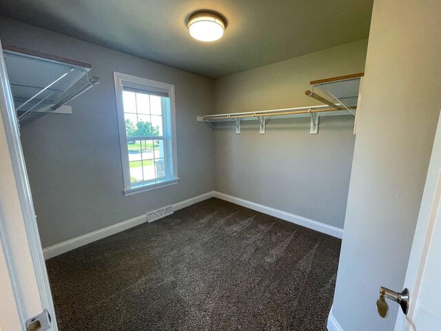 walk in closet featuring visible vents and dark carpet