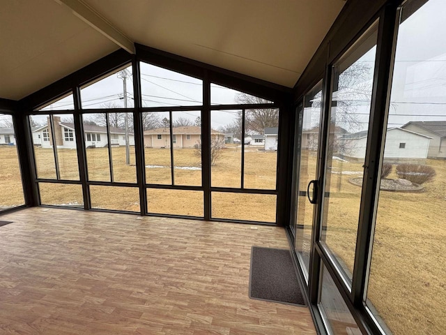 unfurnished sunroom with a residential view, a healthy amount of sunlight, and vaulted ceiling with beams