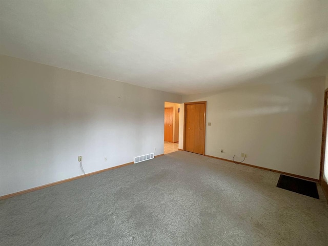 unfurnished room with visible vents, baseboards, and light colored carpet