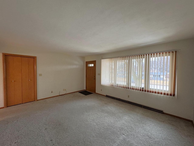 empty room with a baseboard radiator, baseboards, and carpet