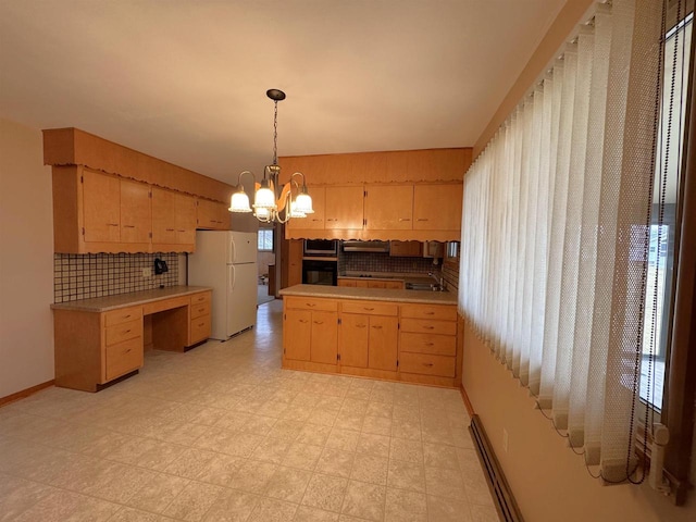 kitchen featuring black oven, an inviting chandelier, light countertops, and freestanding refrigerator