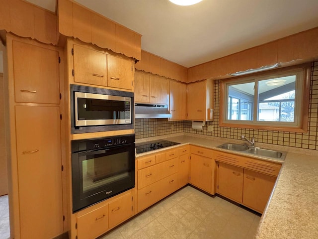 kitchen with black appliances, under cabinet range hood, a sink, light countertops, and light floors