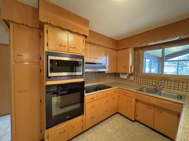 kitchen featuring a sink, black appliances, light countertops, under cabinet range hood, and backsplash