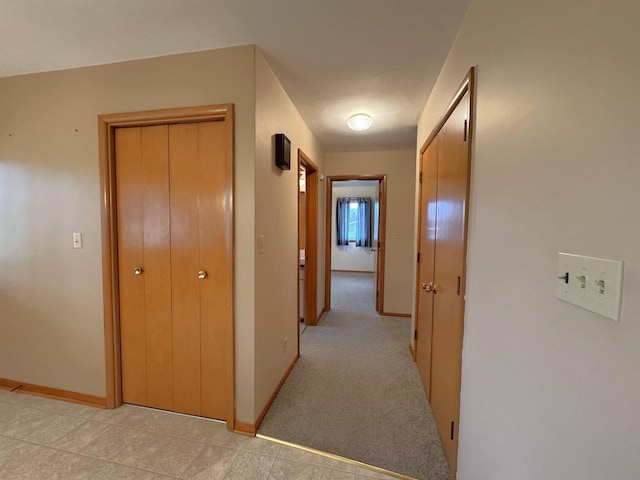 hall featuring baseboards and light carpet