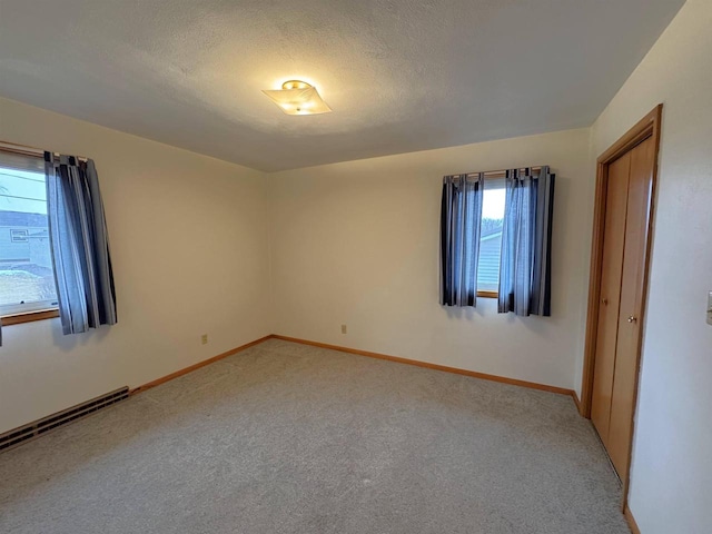 unfurnished room featuring a textured ceiling, baseboards, and light carpet