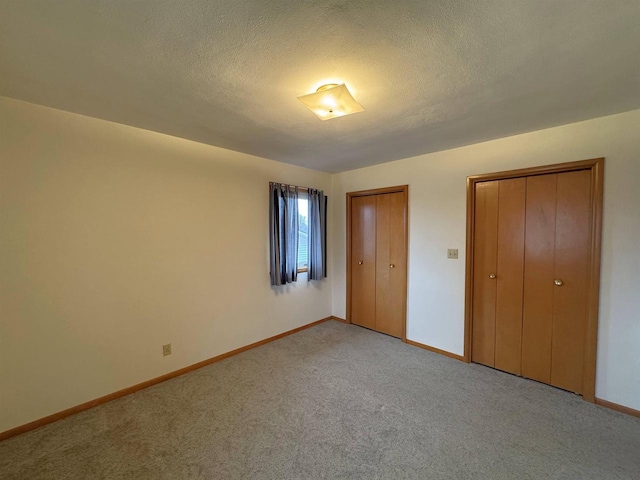 unfurnished bedroom with baseboards, light carpet, and a textured ceiling