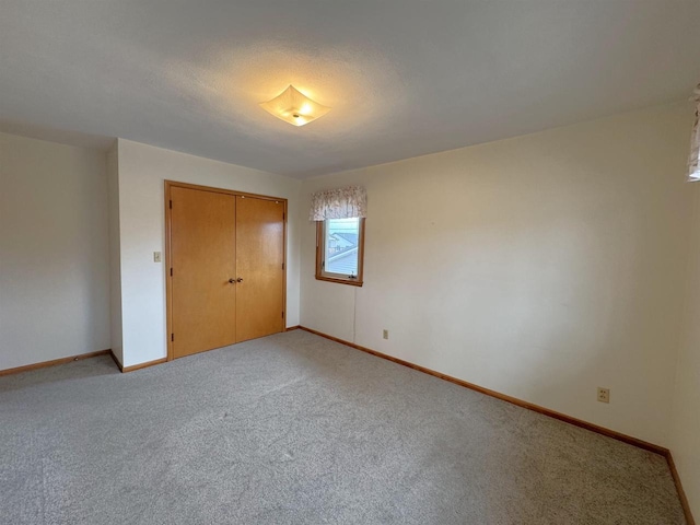 unfurnished bedroom with baseboards, a closet, and light carpet