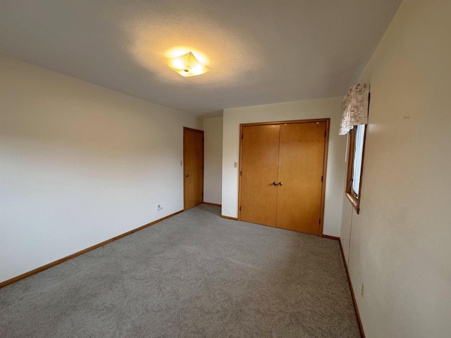 unfurnished bedroom featuring a closet, baseboards, and light carpet