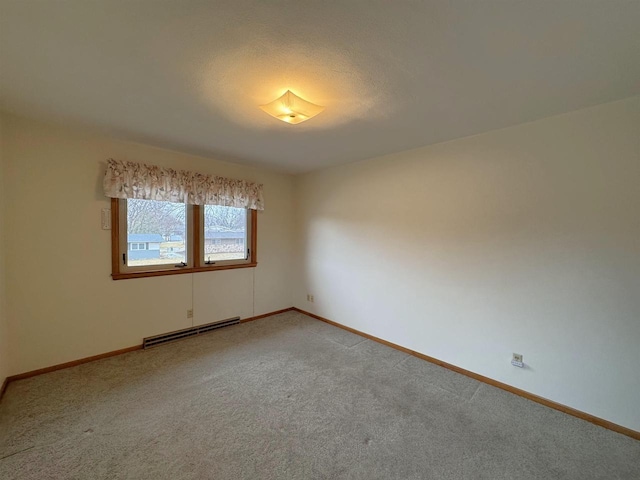 empty room with baseboard heating, light colored carpet, and baseboards