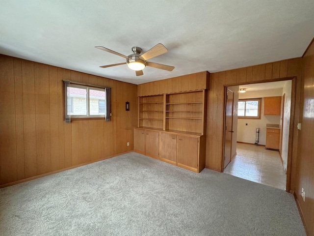 spare room featuring light carpet, wooden walls, and ceiling fan