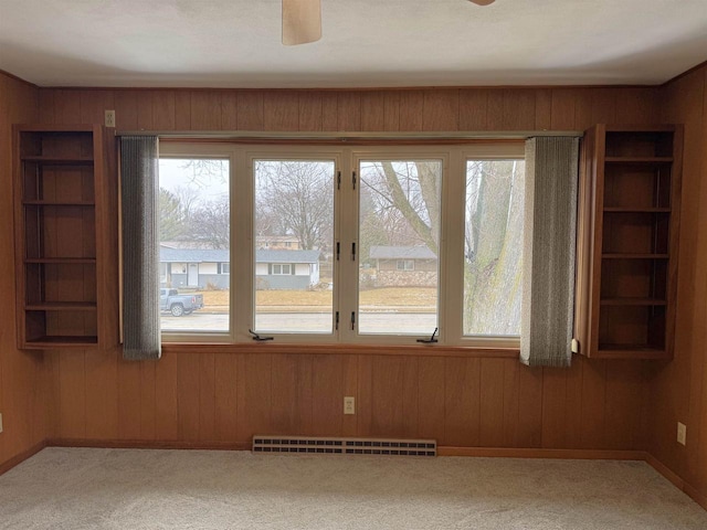 carpeted spare room with plenty of natural light and wood walls