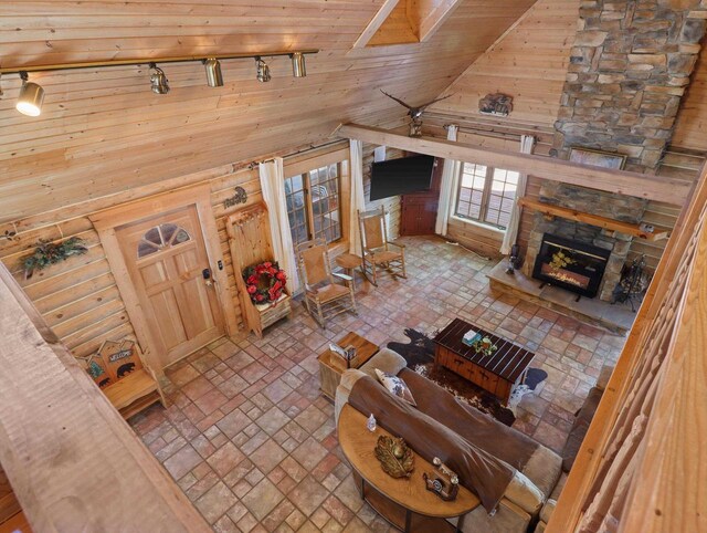 W3864 W Lemonweir Ct, Mauston, WI 53948 - living room with high vaulted ceiling, wood walls, track lighting, a stone fireplace, and brick floor