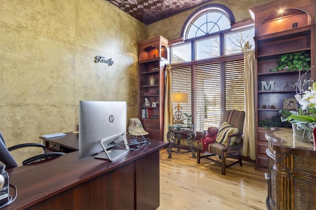 office space featuring light wood-style flooring and a high ceiling