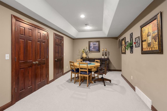 dining space featuring visible vents, baseboards, a raised ceiling, and light colored carpet