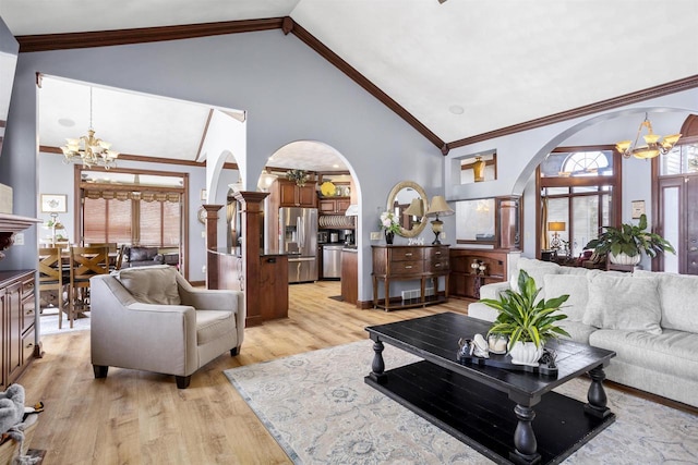 living area with light wood-type flooring, a notable chandelier, high vaulted ceiling, ornamental molding, and arched walkways