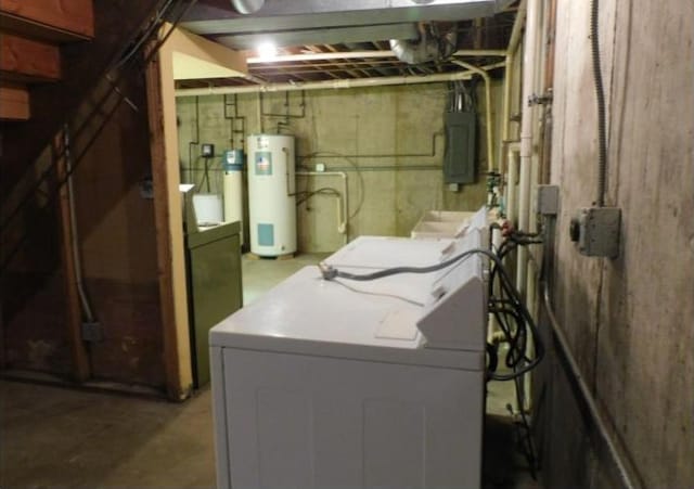 clothes washing area featuring water heater, laundry area, electric panel, and washing machine and clothes dryer