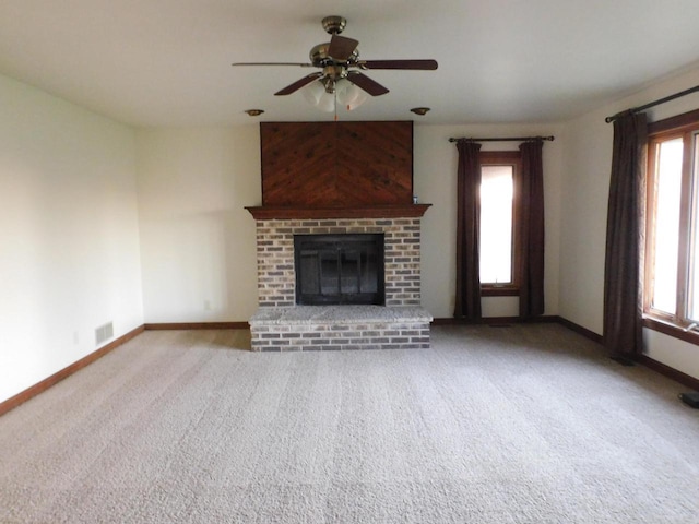 unfurnished living room with carpet, plenty of natural light, a fireplace, and baseboards