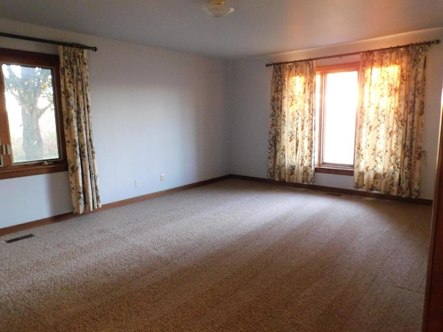 carpeted empty room featuring visible vents and baseboards