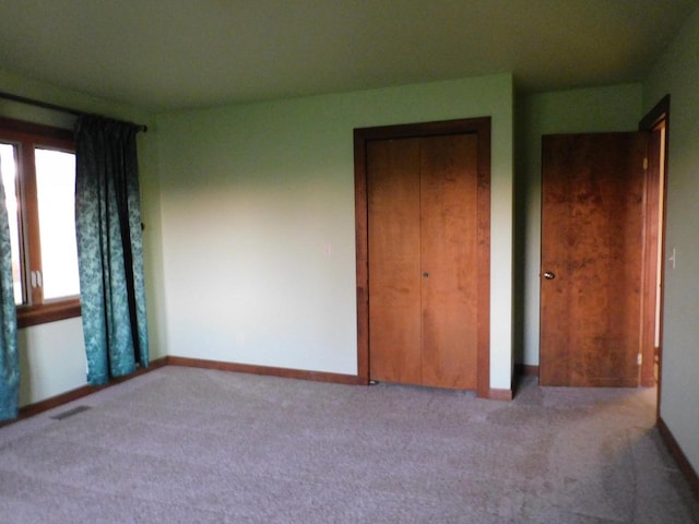 unfurnished bedroom with a closet, baseboards, visible vents, and carpet flooring