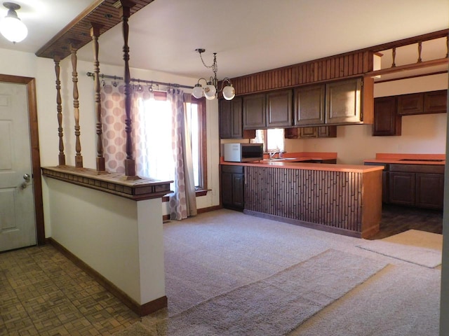 kitchen with a sink, stainless steel microwave, baseboards, and a peninsula