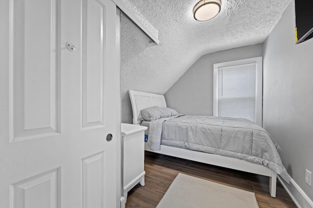 bedroom featuring baseboards, a textured ceiling, wood finished floors, and vaulted ceiling