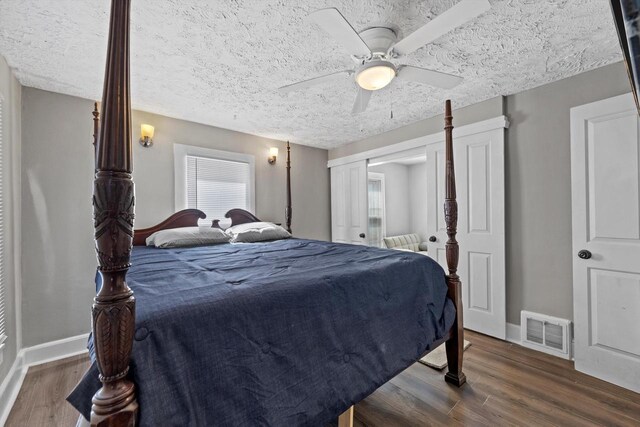 bedroom featuring a ceiling fan, wood finished floors, visible vents, baseboards, and a textured ceiling