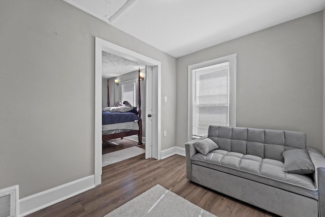 living area with attic access, wood finished floors, visible vents, and baseboards