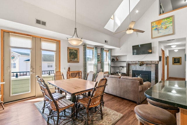 dining room with a skylight, wood finished floors, visible vents, and a tile fireplace