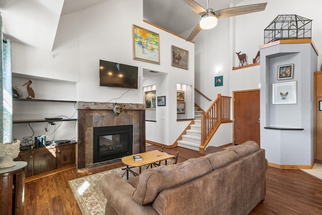 living room with stairway, a tile fireplace, a high ceiling, and wood finished floors