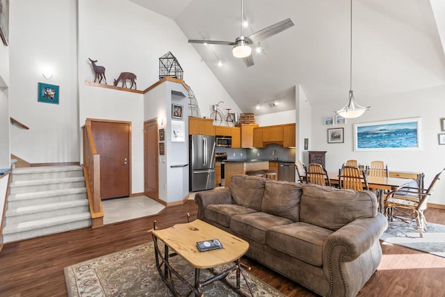 living area with stairs, a ceiling fan, baseboards, and light wood finished floors