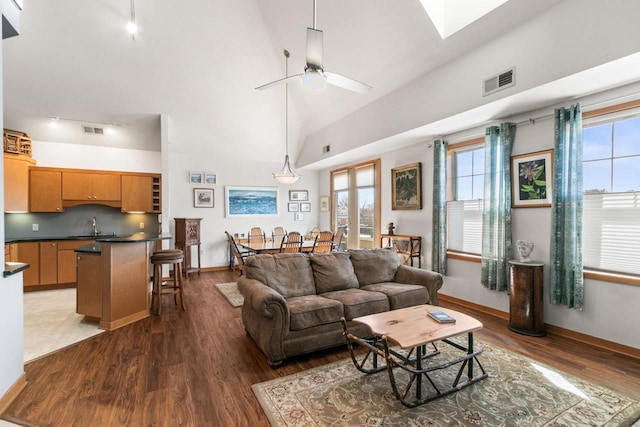 living room featuring wood finished floors, visible vents, and high vaulted ceiling