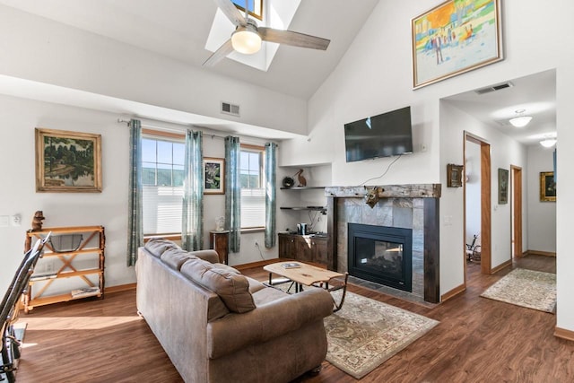 living room featuring a tiled fireplace, visible vents, high vaulted ceiling, and wood finished floors