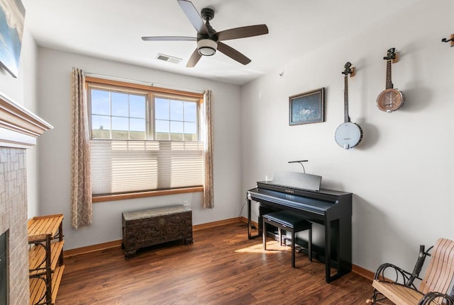 sitting room with a ceiling fan, dark wood-style floors, visible vents, baseboards, and a fireplace