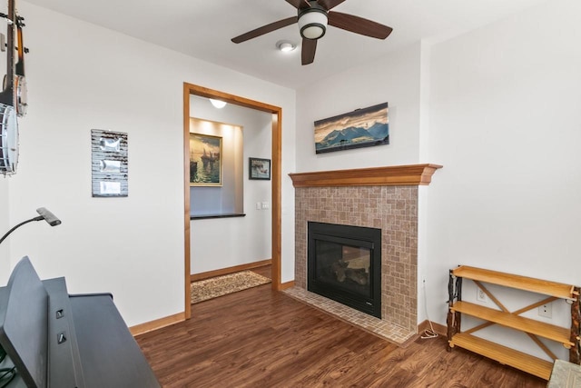 living area with baseboards, a brick fireplace, and wood finished floors