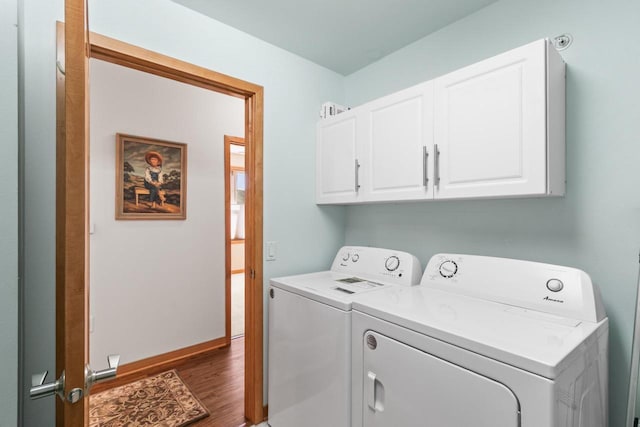 laundry area featuring washer and dryer, cabinet space, dark wood-style flooring, and baseboards