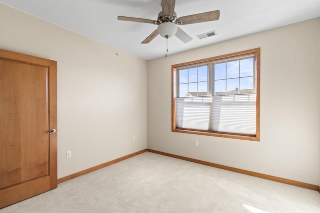 spare room with light carpet, visible vents, a ceiling fan, and baseboards