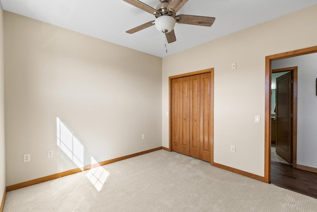 unfurnished bedroom featuring a closet, baseboards, light carpet, and ceiling fan