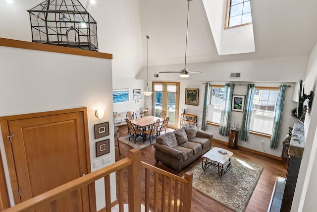 living area with visible vents, high vaulted ceiling, wood finished floors, baseboards, and ceiling fan