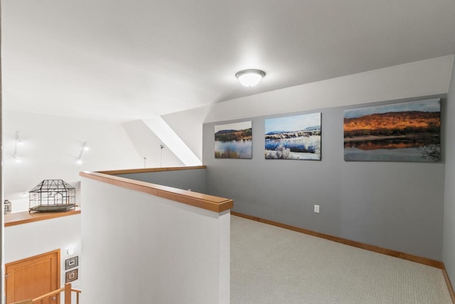 hallway featuring baseboards, an upstairs landing, and carpet floors