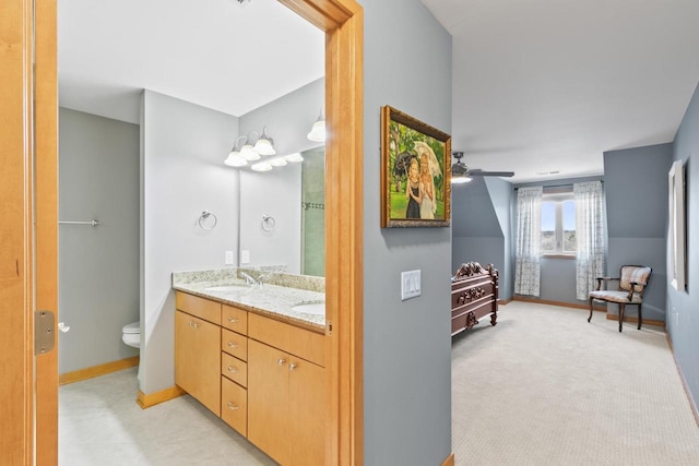 full bathroom with baseboards, toilet, double vanity, a ceiling fan, and a sink