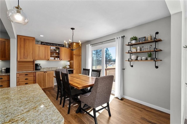 dining room featuring a chandelier, baseboards, and wood finished floors