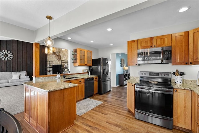 kitchen featuring glass insert cabinets, light wood-type flooring, a peninsula, black appliances, and a sink