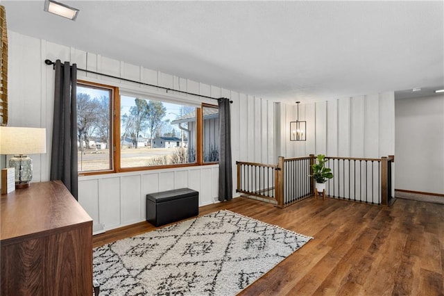 sitting room with an upstairs landing, a notable chandelier, and wood finished floors